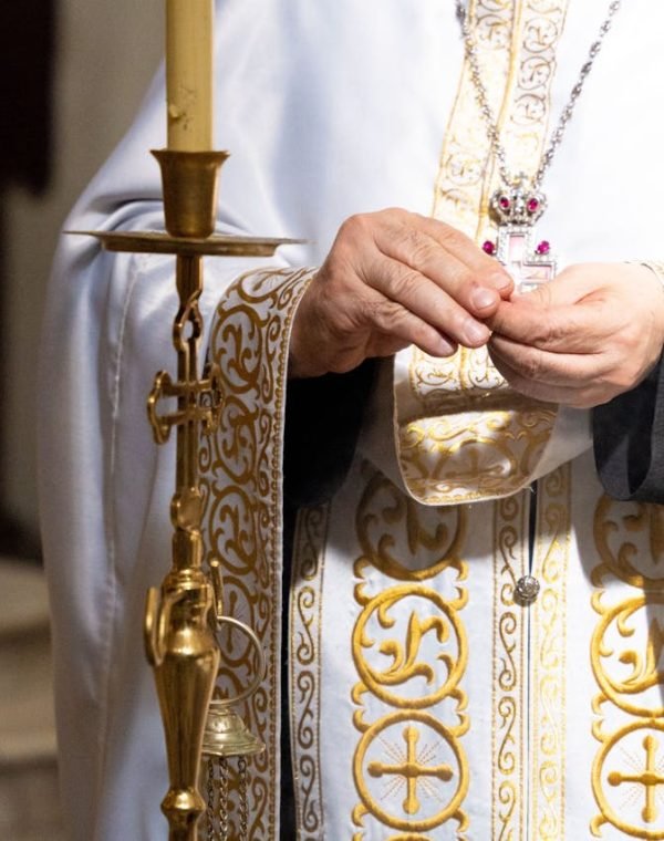 A priest wearing ornate vestments performs a sacred ritual in a church.
