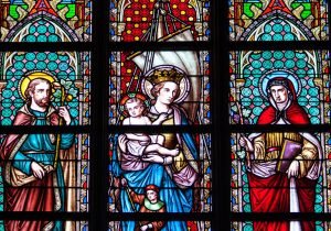 Colorful stained glass depicting saints and religious figures in a Brussels cathedral.