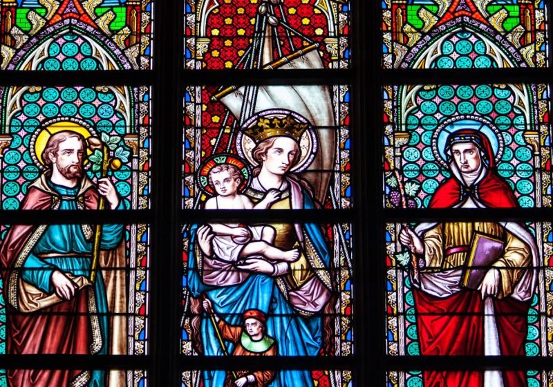 Colorful stained glass depicting saints and religious figures in a Brussels cathedral.